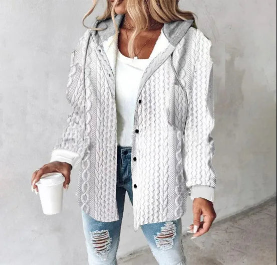 Woman wearing a white knitted cardigan over a white shirt and jeans, holding a coffee cup.