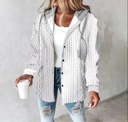 Woman wearing a white knitted cardigan over a white shirt and jeans, holding a coffee cup.
