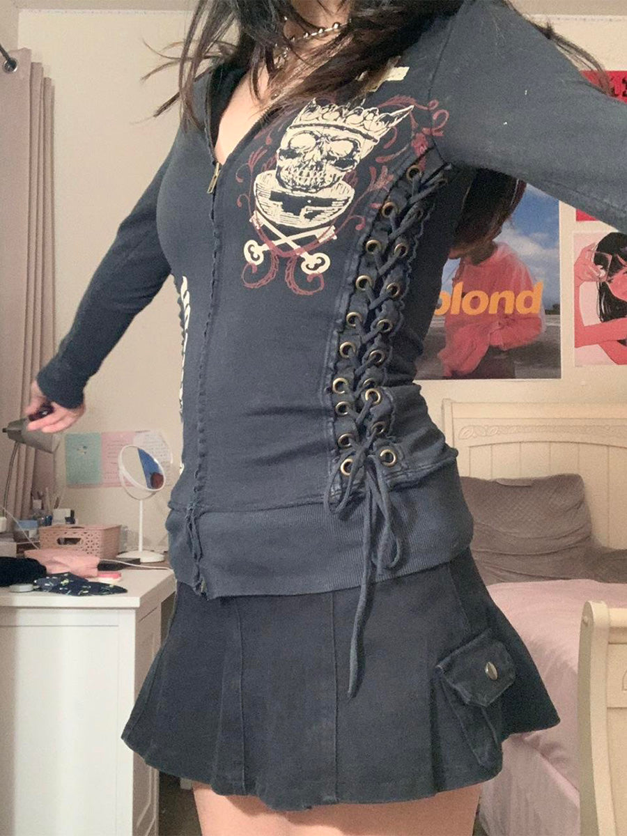 Person wearing a dark blue lace-up top and skirt in a room with posters on the wall.