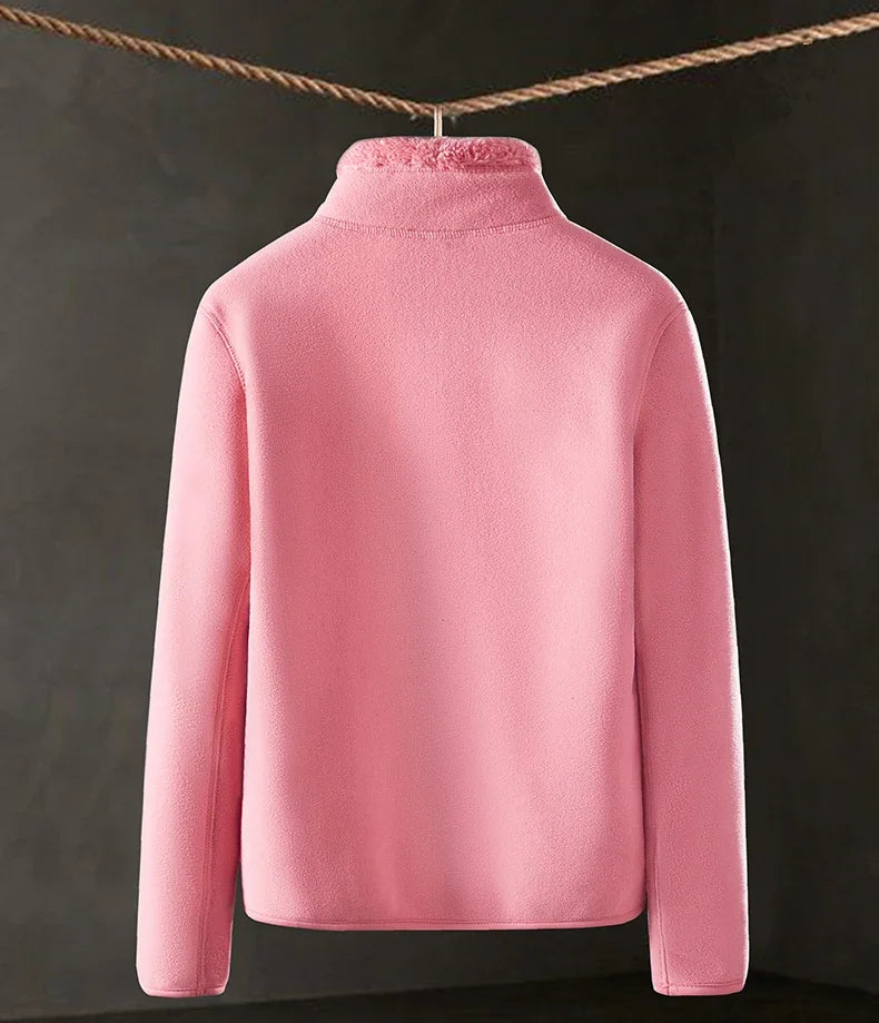 Pink fleece jacket hanging on a line against a dark background
