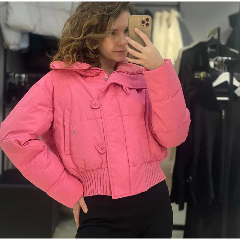 Person wearing a pink jacket taking a mirror selfie in a clothing store.